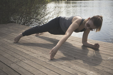 Young girl practices yoga on the shore of the lake, the concept of enjoying privacy and concentration