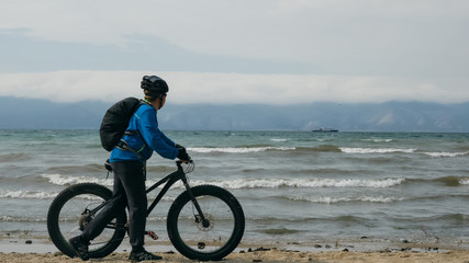 Fototapeta premium Fat bike also called fatbike or fat-tire bike in summer driving on the beach. The guy is going straight on the beach. On the sand on such a bike ride is not difficult.