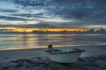 A beautiful tropical dawn with a boat on beach