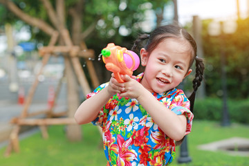 Cheerful kid girl playing water gun at Songkran festival on summer season in thailand (Thai new year - water festival).
