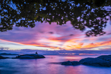 Exposure boy stay on the rock stone on Pattaya beach at sunset time with blue cloud and sunset time background.