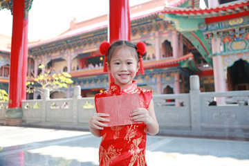 Happy little Asian child girl holding gold and red envelope on white background during chinese new...