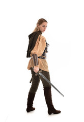 full length portrait of girl wearing medieval costume with sword. standing pose with back to the camera, isolated on white studio background.