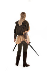 full length portrait of girl wearing medieval costume with sword. standing pose with back to the...