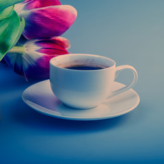 cup of coffee and red tulips lie on the gray surface of the table.
