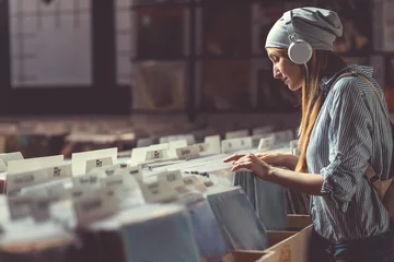 Fotobehang Muziekwinkel Aantrekkelijk meisje dat naar muziek luistert in een muziekwinkel