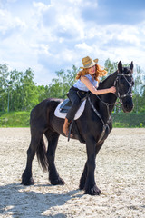 Woman enjoying horse company. Young Beautiful Woman in straw hat With black Horse Outdoors, stylish girl at american country style 