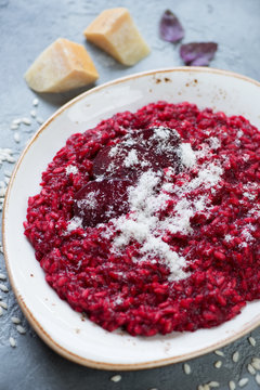 Close-up of beetroot risotto topped with grated parmesan cheese, vertical shot, selective focus
