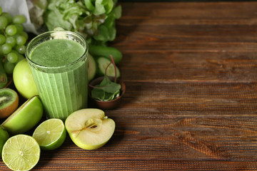 Glass of tasty smoothie and ingredients on wooden table