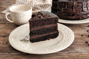 Plate with piece of delicious chocolate cake on wooden table