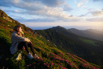 Naklejka na ściany i meble Woman sitting on mountain top and contemplating the sunset