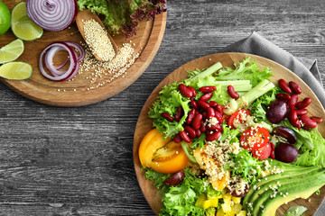 Plate with quinoa salad on wooden background, top view