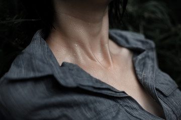 Women's collarbone and neck. Water drops on the skin. Woman in wet clothes under the summer rain