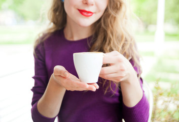 Beautiful woman with red lips holing white cup of coffee