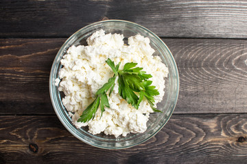 Fresh plain homemade yougurt and cottage cheese (yogurt, youghurt, kefir, ayran, lassi) in glass with herbs over wooden background, copy space. Probiotic cold fermented dairy drink.