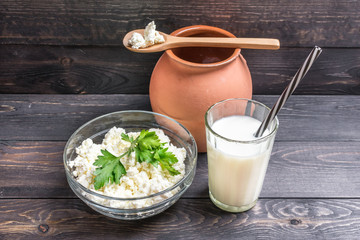 Fresh plain homemade yougurt and cottage cheese (yogurt, youghurt, kefir, ayran, lassi) in glass with herbs over wooden background, copy space. Probiotic cold fermented dairy drink.