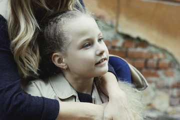 Smiling beautiful girl 7 years old with blue eyes, hugging her mother