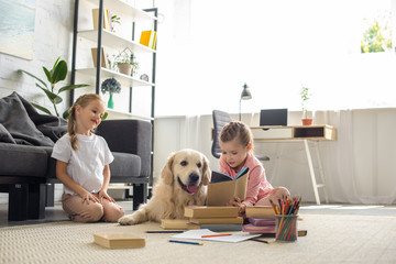 little sisters reading books with golden retriever dog near by at home