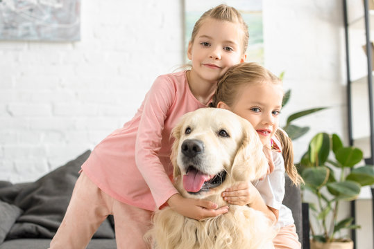 portrait of adorable kids hugging golden retriever dog at home