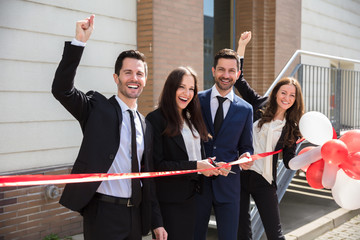 Happy Businesspeople Cutting Ribbon