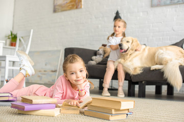 selective focus of little sisters with books and golden retriever dog near by at home