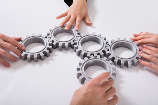 Businesspeople Joining Gears On Desk