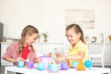 cute little sisters pretending to have tea party together at home