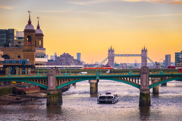 Orange sunset with London cityscape, including Southwark bridge, Cannon Street railway bridge and...