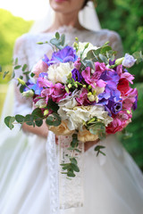 Wedding bouquet of flowers including Red hypericum, Roses, Lilies of the valley, mini Roses, Seeded Eucalyptus, Astilbe, Scabiosa, Pieris, and ivy