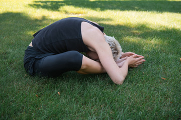 side view of woman practicing yoga on grass in park