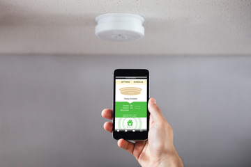 Person Operating Smoke Detector With Mobile Phone
