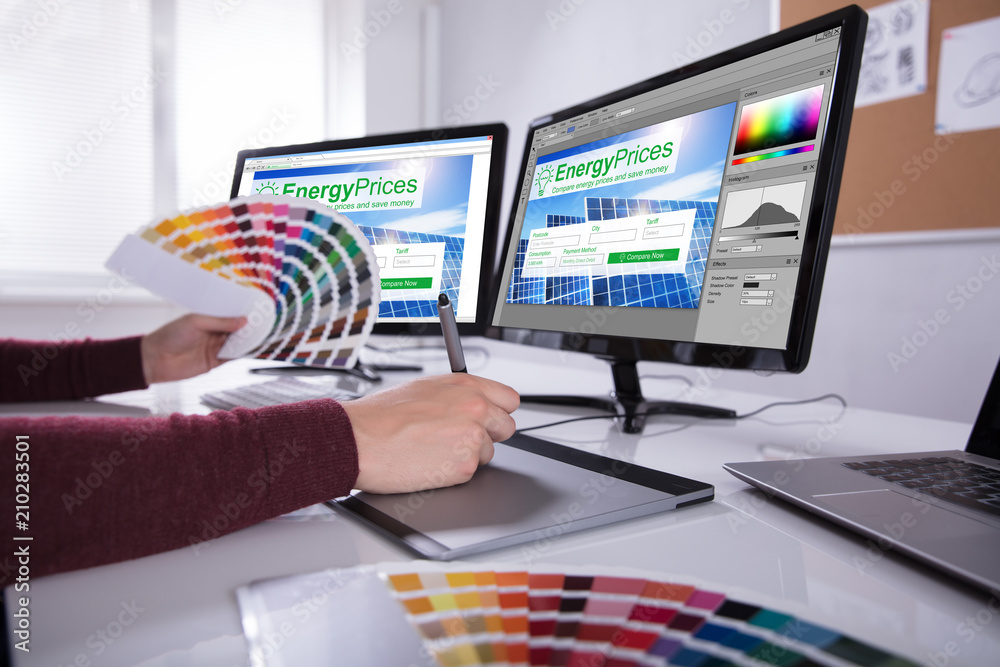 Poster Designer Working On Multiple Computer Screens