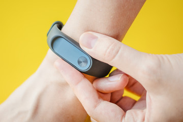 woman using fitness tracker on hand at yellow background