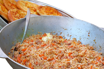 Uzbek pilaf in in big metal bowl on background of bread tortillas isolated on white background
