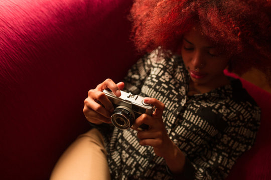 Young ethnic woman with camera on couch