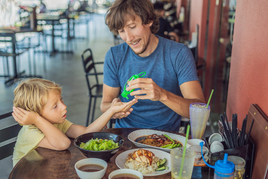 Father and son using wash hand sanitizer gel before eating in a cafe