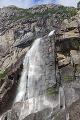 Water falls from steep rocks and disperse into spray veil on the mountain slopes beside Lysefjord, Rogaland, Norway