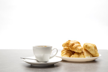 Cup of fresh coffee with croissants on dark background