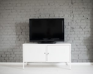 Modern flat lcd television set on white cabinet.