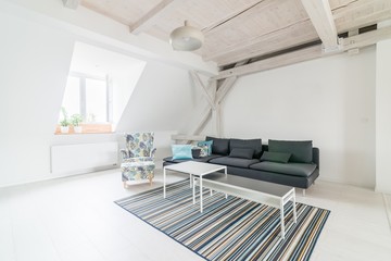 Bright attic living room with wooden ceiling beams.