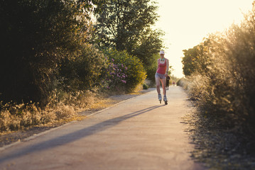 Young sportswoman having  fun while roller skating durin sunset