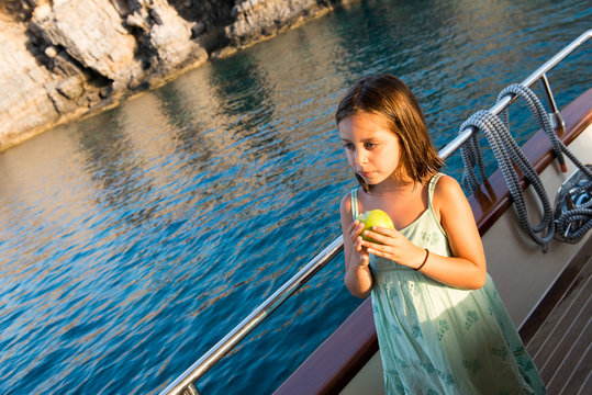 cute girl is eating her apple at boat