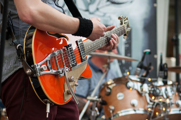 closeup of guitarist playing guitar with rock group in the street