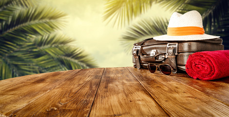 Summer suitcase of brown color and background of exotic palms 