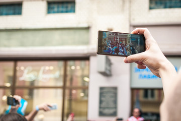 Shooting mobile phone with hands, against the crowd of people