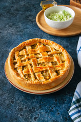 Homemade young cabbage pie from flaky dough  served on a plate. Blue stone background.