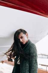 Girl posing near the yacht.Beautiful brunette posing.Girl with an earring up her nose.Summer evening the girl and the boat.