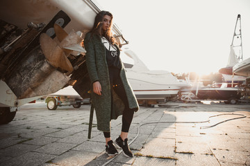 Girl posing near the yacht.Beautiful brunette posing.Girl with an earring up her nose.Summer evening the girl and the boat.