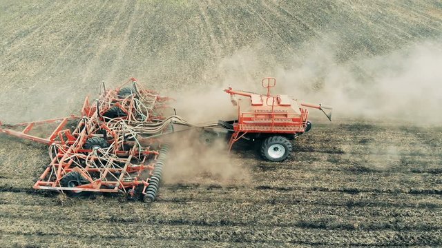 Agricultural tractor across a massive field. Sowing agricultural crops at field.