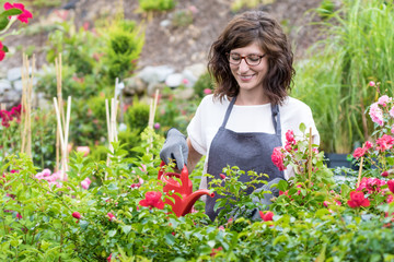 Lächelnde Floristin beim gießen der Rosen